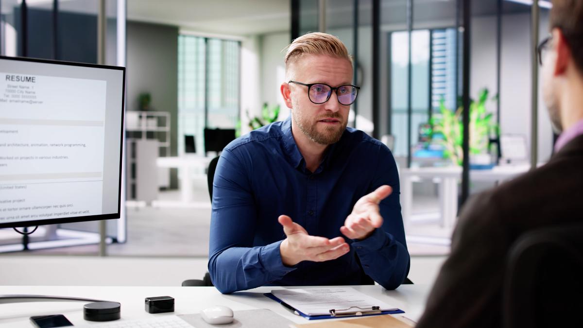 A professional man speaking during a virtual job interview, illustrating how to use the STAR method to answer behavioural questions.How to Use the STAR Method in Job Interviews