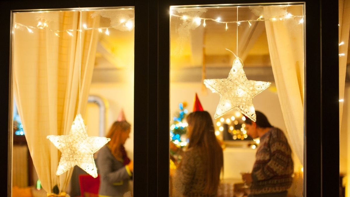 Warm holiday scene viewed through a window with people talking, representing genuine seasonal connection and networking.