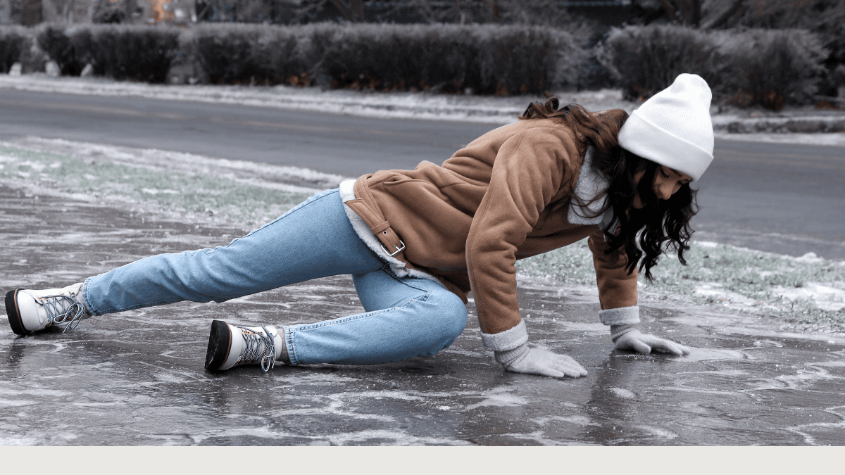 Woman slipping on ice during winter, illustrating the risk of slips, trips, and falls in icy conditions.