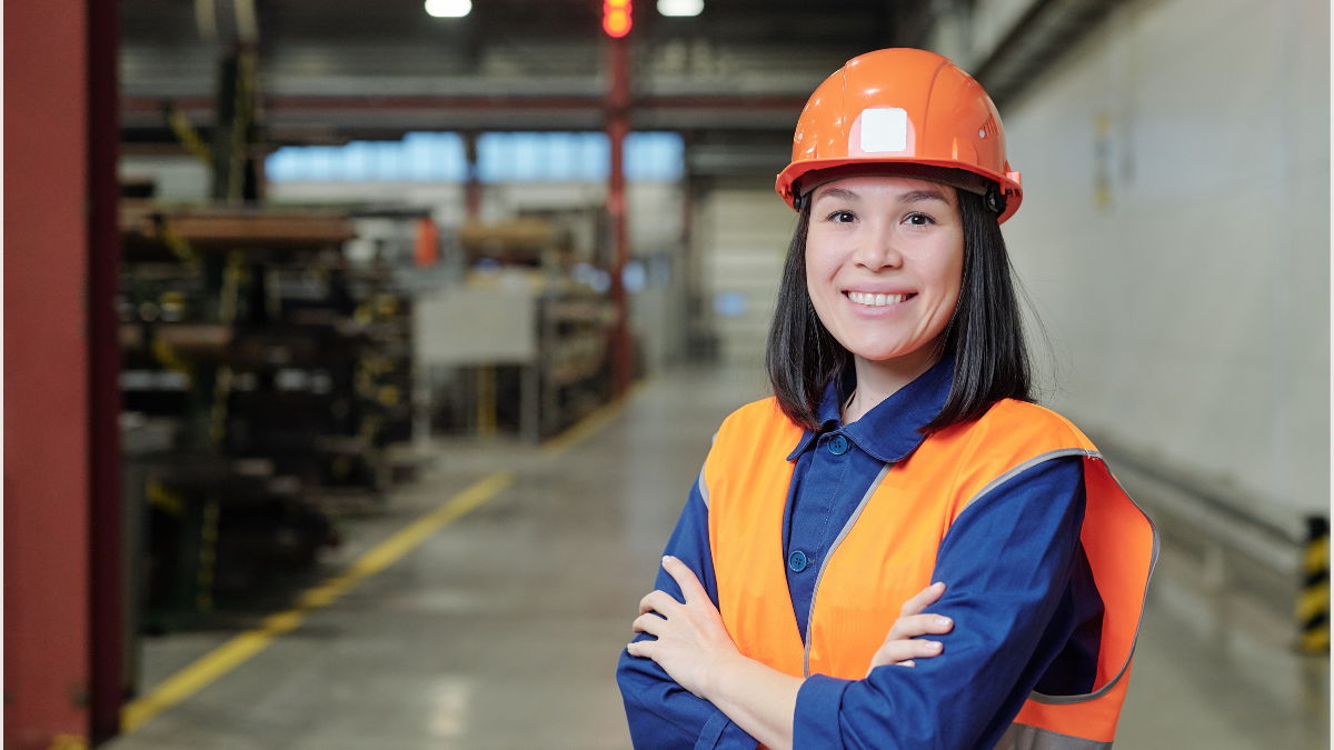 Female engineer wearing a hard hat and safety vest standing inside an industrial facility in Canada.